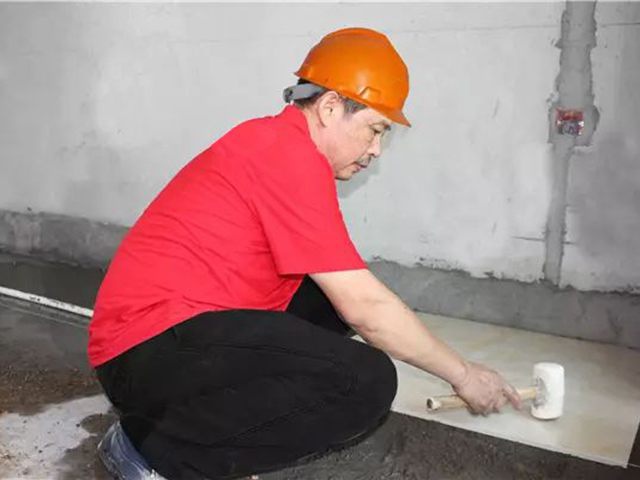 5鋪貼地磚時(shí)，磚的背面朝上批刮水泥油，并按箭頭所指方向統(tǒng)一鋪貼，用橡皮錘從中到邊，由重到輕敲實(shí).jpg